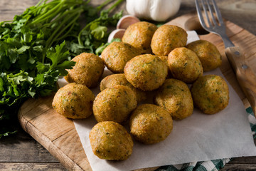 Traditional cod fritters decorated with garlic and parsley on wooden table	
