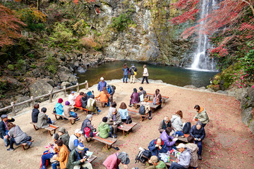 People resting and enjoying waterfall and autumn colors