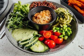 Healhty vegan lunch bowl with ingredients. humuss, cucumber, tomatoes, rucola.