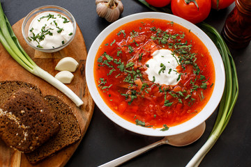 Traditional Ukrainian Russian borscht with white beans on the bowl. Plate of red beet root soup borsch on black rustik table. Traditional Ukraine food cuisine
