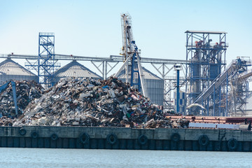 in port loading scrap metal on a barge