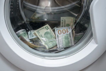 Many banknotes are inside Washer. A lot of cash dollars is washed in the drum of a washing machine....