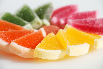 Tasty sweet marmalade in the shape of fruit slices on a white background