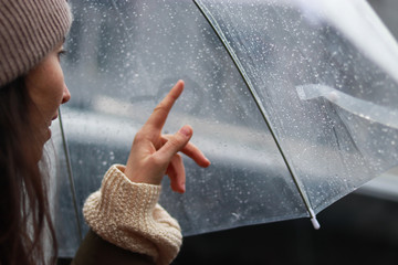girl is painting the heart on a foggy surface in the rain under an umbrella. Love story concept