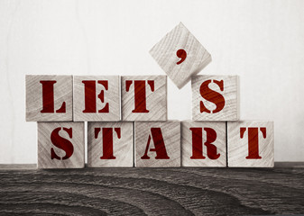 the words let's start in old wood type - wooden cubes. Business startup concept