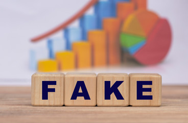 The concept of the word FAKE on cubes against the background of the graph
