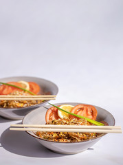 Funchosa with vegetables on a grey plate on a white background, selective focus. Rice noodles with mushrooms mun and vegetables, prepared for wok.