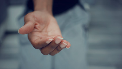 Black woman offering a helping hand. Closeup and selective focus on her fingers.