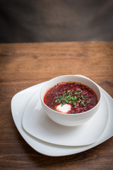 Red borscht soup with dill in white bowl.
