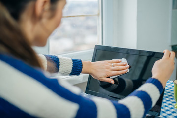 people, housework, electronics and housekeeping concept - close up of woman hand cleaning laptop computer screen with cloth