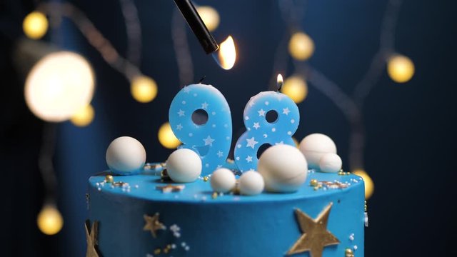 Birthday cake number 98 stars sky and moon concept, blue candle is fire by lighter and then blows out. Copy space on right side of screen if required. Close-up and slow motion