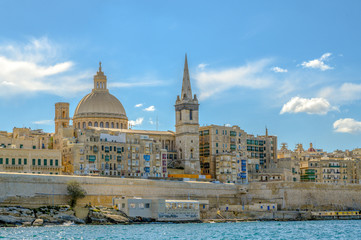 Fototapeta na wymiar A view of Valletta from the seafront showing the dome of the Basilica of Our Lady of Mount Carmel and St Paul's Pro-Cathedral.