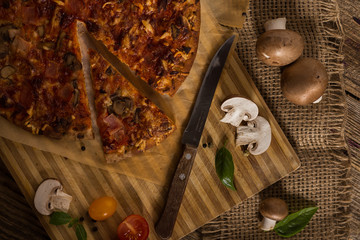 Pizza with mushrooms, salami and wegetable on the old wustic wood table.