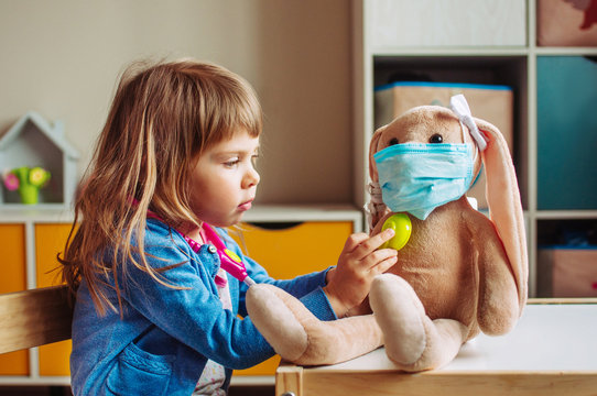Little girl playing doctor with rabbit soft toy in the kids room