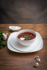 Red borscht soup with dill in white bowl.