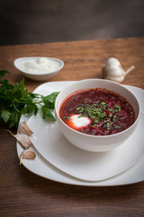 Red borscht soup with dill in white bowl.