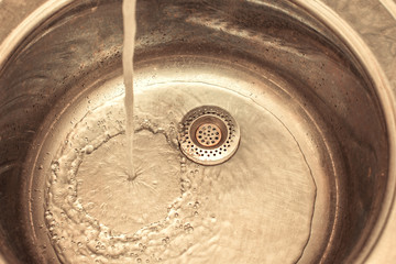 A stream of water pours into the iron sink.