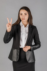 Young business woman in dark suite on grey background.