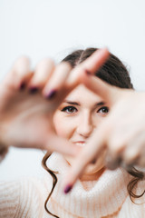 brunette girl doing camera hands and fingers on a white background