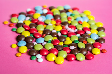 Fototapeta na wymiar Pile of Colorful Chocolate Coated Candy on a Pink Background