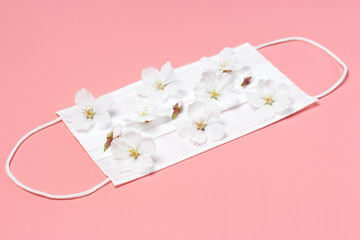 Medical mask with little white flowers on pink background.