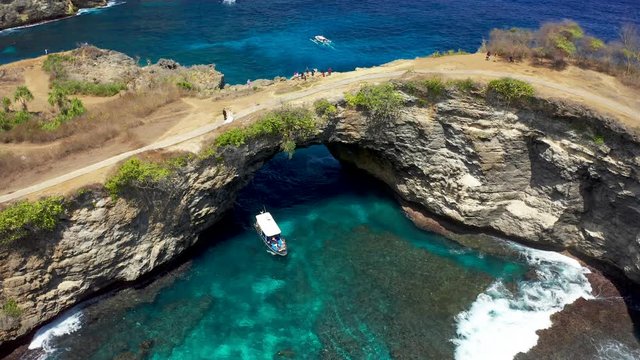 Aerial view of tourist speedboat at azure sea in Broken Beach, Nusa Penida, Bali, Indonesia. Aerial 4K