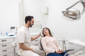 Fototapeta premium Portrait of a bearded dentist male explaining procedure to a female patient