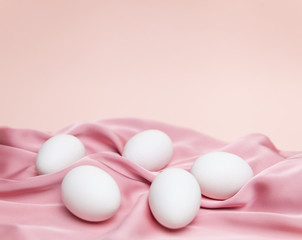 Creative Easter beige and pink background with white eggs.