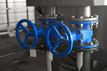 two big blue tap or valve or faucet on water pipe on gray industrial background