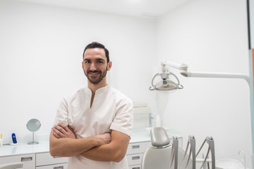 Portrait of a smiling doctor male posing in an dentist office