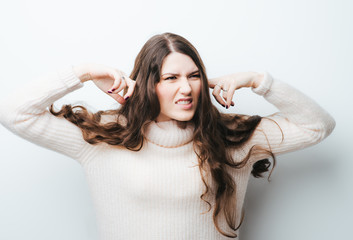 Closeup portrait attractive peaceful relaxed looking young woman covering her ears isolated grey office wall background. Hear no evil concept idea. Human emotion facial expression attitude