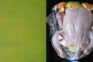 Raw chicken with apples in the plastic oven bag on the backing tray