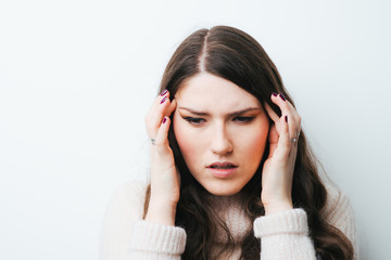 Fototapeta premium Young woman holding her head in pain suffering from a headache on a white background