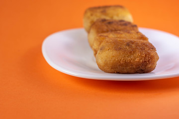 Croquettes or traditional Spanish homemade croquettes on a white plate. Tapas food.