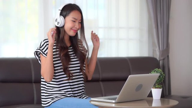Beautiful Girl Selects Song on Laptop Listens to Music with Headphones