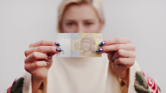 Woman is holding a banknote of One Ukrainian Hryvnia in the hands. Soft selective focus