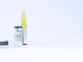 Close up shot of a generic ampoule with Coronavirus Vaccine labelled on it and injection syringe.