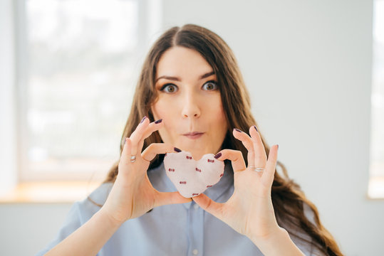 Picture of a small white heart in hands, female holds handmade sewn soft toy,  woman with Valentine gift, happy girl smiling, conceptual image of health care or love