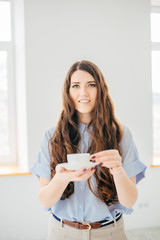 Woman with cup of tea has a rest near the window