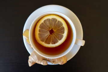 
Cup of tea with lemon and ginger close-up on a black background. Alternative medicine to...