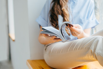 home and leasure concept - smiling woman reading magazine at home near the window