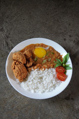 Home cooked japanese curry with white rice, fresh egg yolk, fried chicken karaage as lunch.                       