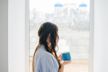 Girl with a cup in profile at the window