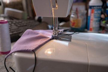 sewing a face mask at home due to covid-19 epidemic, sewing machine close up with cotton fabric