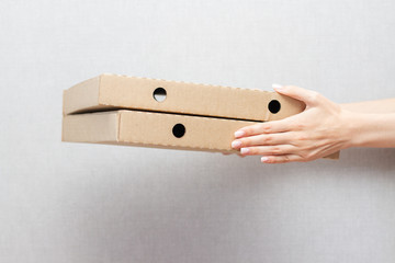 two packs of pizza in female hands on a gray background