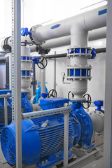 blue high-pressure pumps engines and gray pipes, water or wastewater treatment facilities inside, industrial interior