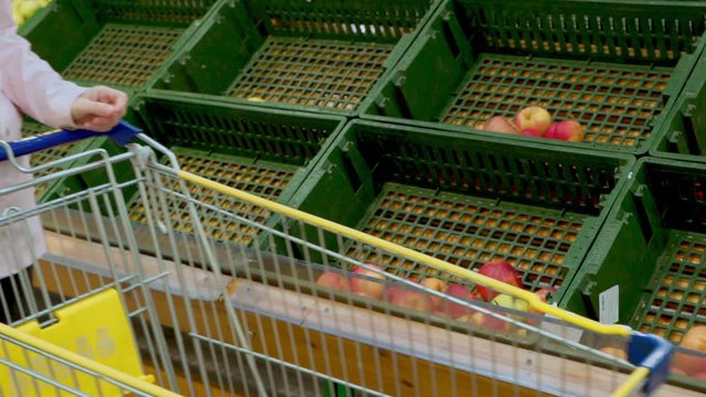Woman with a grocery cart drives past empty fruit shelves