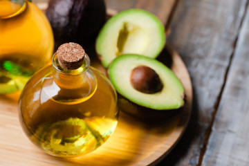 Concept of natural organic oil in cosmetology. Moisturizing skin care and aromatherapy. Gentle body treatment. Atmosphere of harmony relax. Wooden background, avocado. Close up, macro
