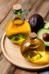 Concept of natural organic oil in cosmetology. Moisturizing skin care and aromatherapy. Gentle body treatment. Atmosphere of harmony relax. Wooden background, avocado. Close up, macro
