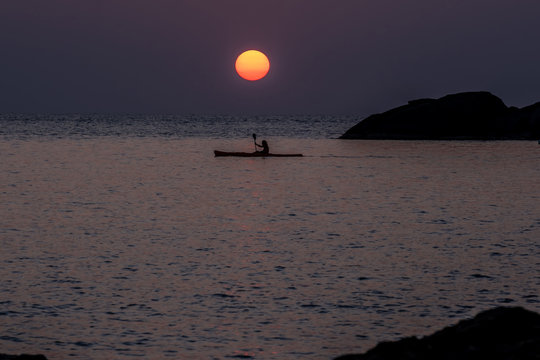 Silhouette man padding canoe and big sun above sea horizon at sunset. Big sunset over the sea in Thailand.